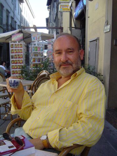 Zu sehen ist der Komoponist Salvatore Sciarrino in einem gelben Hemd und einer Espressotasse in der Hand.