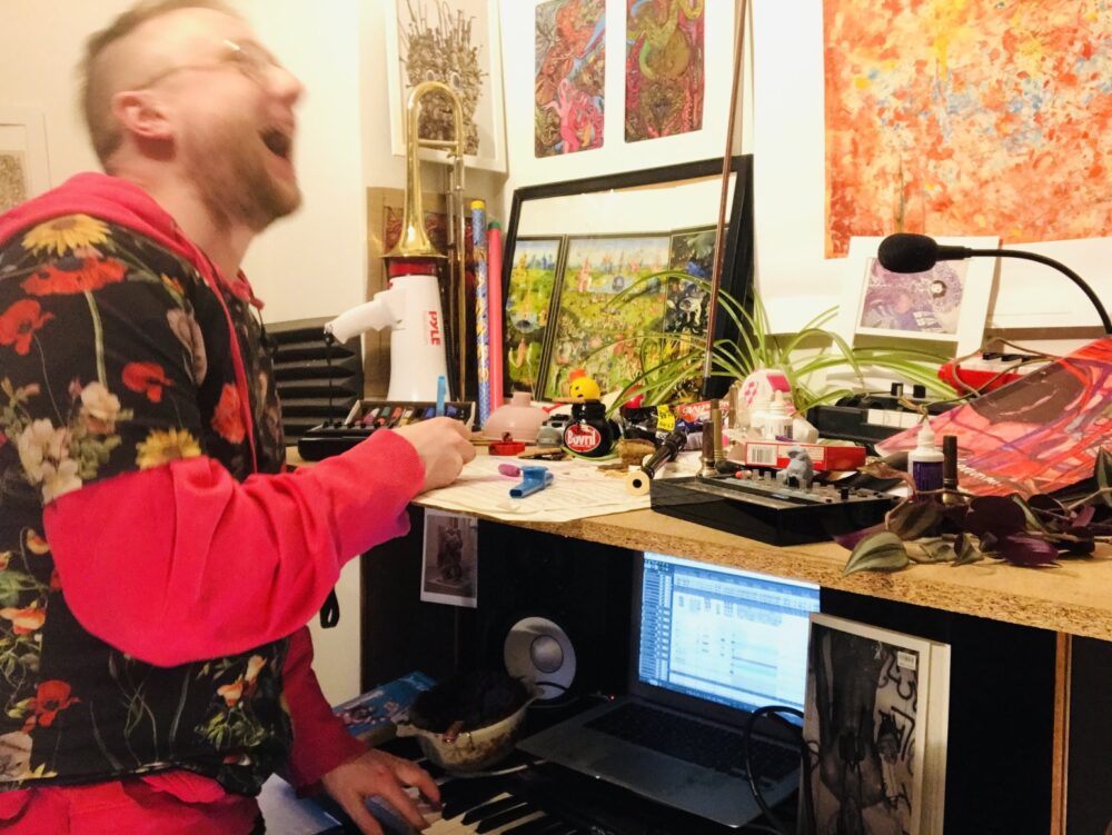 Zu sehen ist der Komponist Alex Paxton während er an einem Keyboard spielt. Sein Gesicht ist durch eine schnelle Bewegung verschwommen.