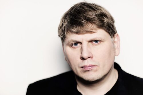 Das Porträt eines Mannes (Sergej Newski). Er blickt geradeaus und trägt ein schwarzes Oberteil.