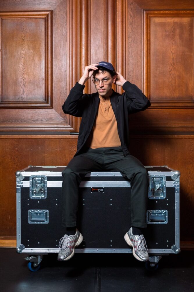 Andreas Eduardo Frank auf einem Flightcase sitzend.