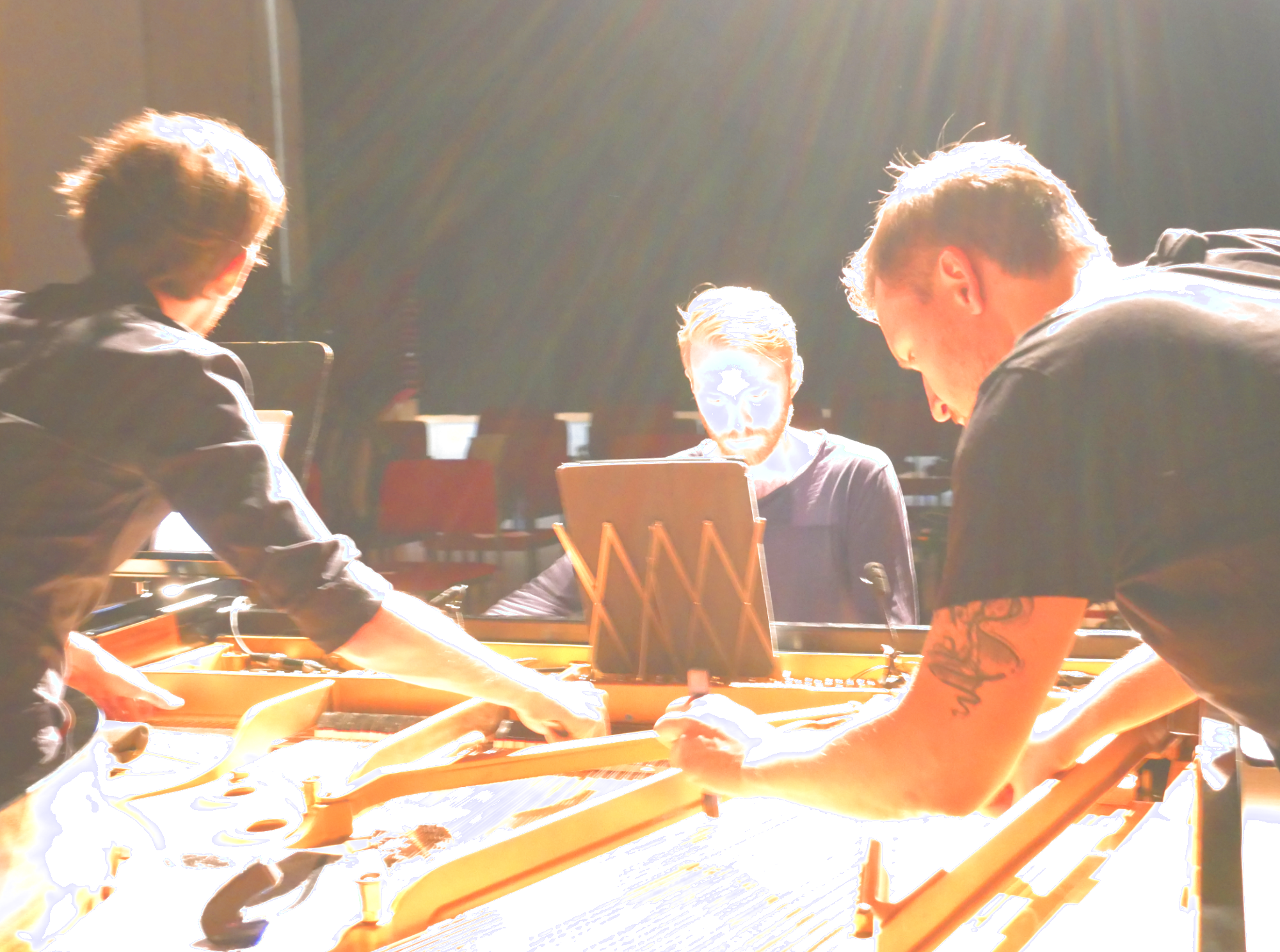 Zu sehen ist das Trio Pony Says, zu dritt bespielen sie einen Flügel: Felix Nagl spielt an den Tasten, Lucas Gerin und Thilo Ruck bespielen die Saiten im Innenraum.